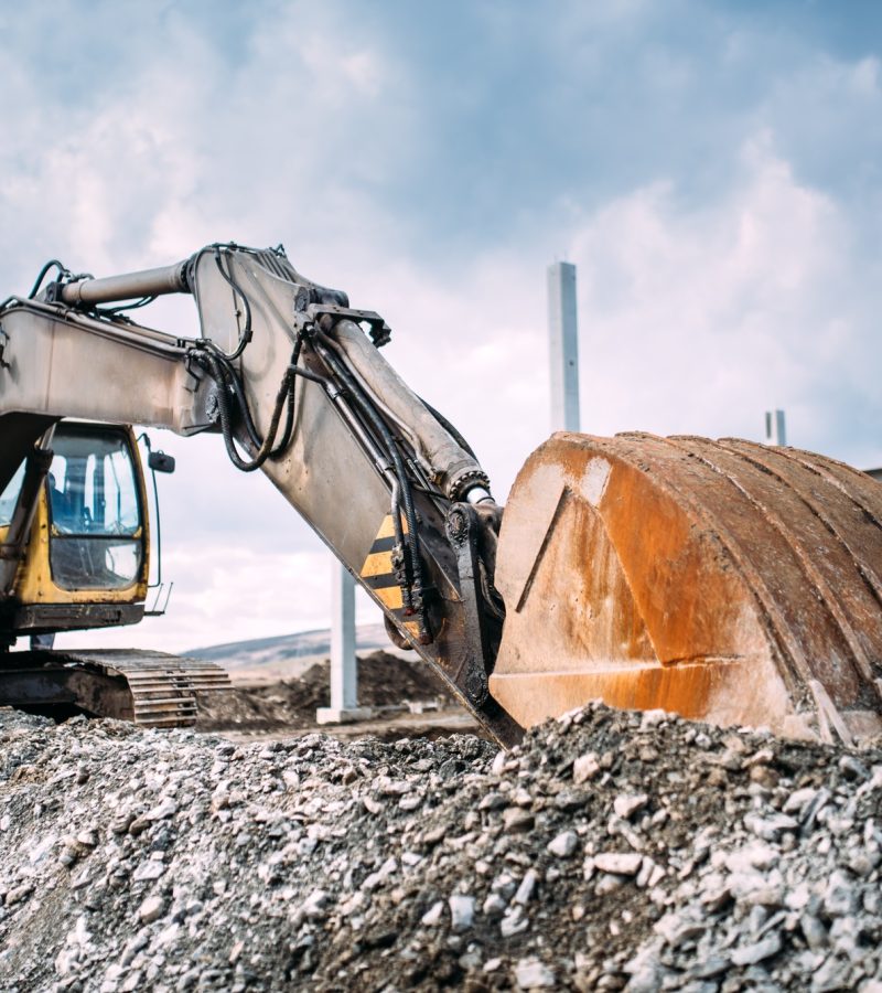 Industrial heavy duty excavator moving gravel on highway construction site